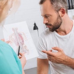 chiropractic-showing-human-body-picture-to-male-patient-during-appointment-in-clinic-e1683512865598.jpg